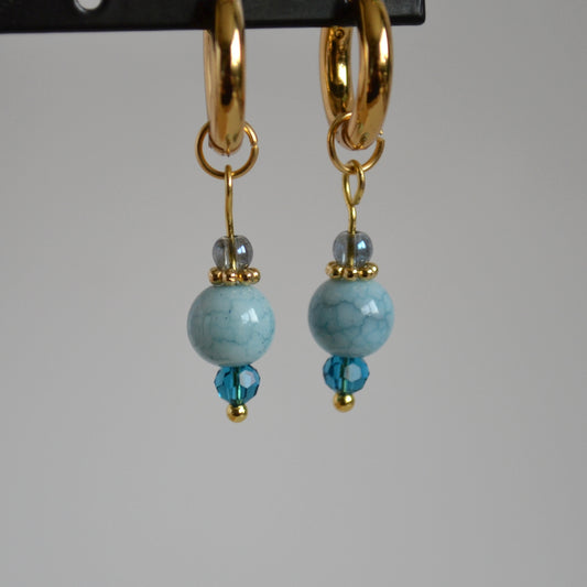Oorbellen goudkleurig met lichtblauw kristalglas en natuursteen look hanger