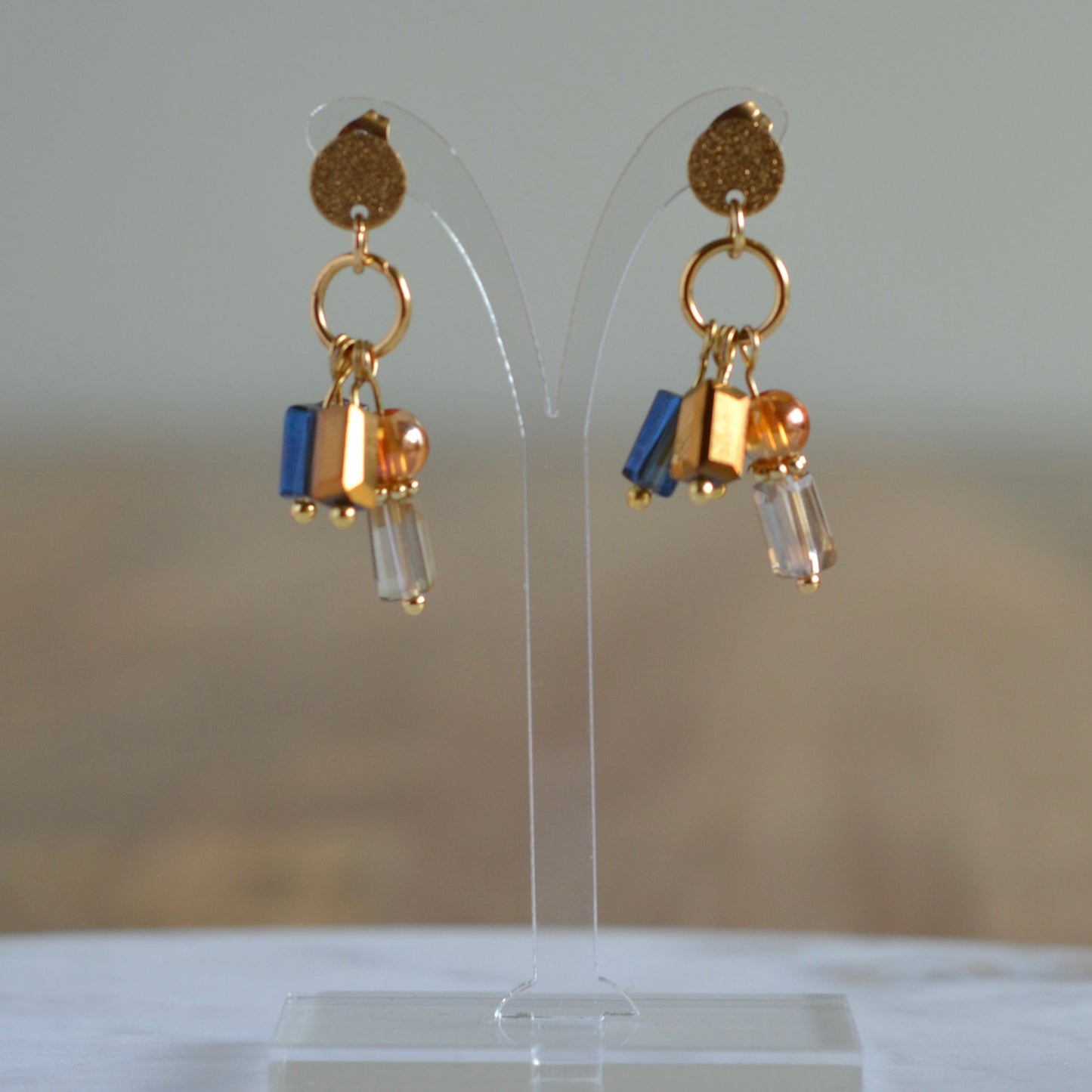 Amber Twist – goudkleurige oorbellen met amber en blauwe accenten