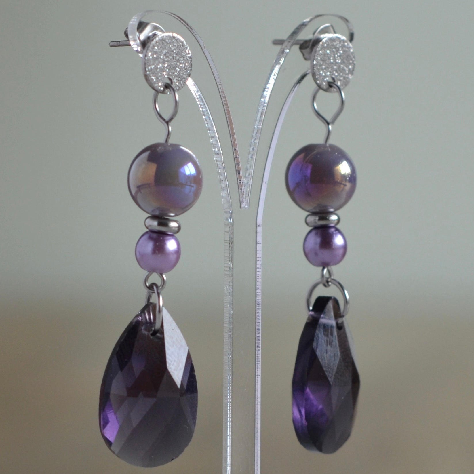Zilverkleurige oorbellen met iriserende paarse kralen en facetgeslepen druppel