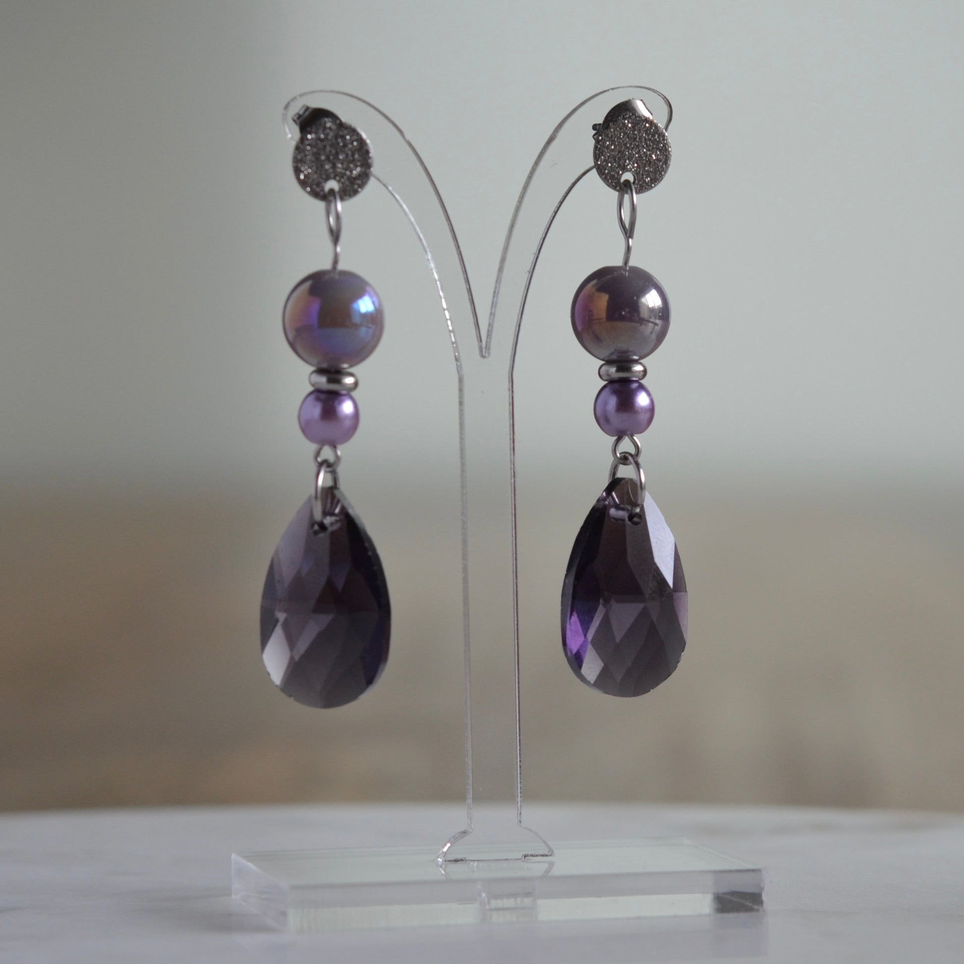 Zilverkleurige oorbellen met iriserende paarse kralen en facetgeslepen druppel
